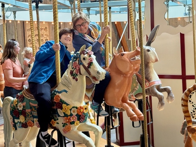 Couple sitting in red and yellow Muskoka chairs facing ocean
